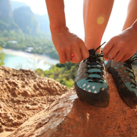 Eine Frau trägt Kletterschuhe und bindet gerade eine Schleife