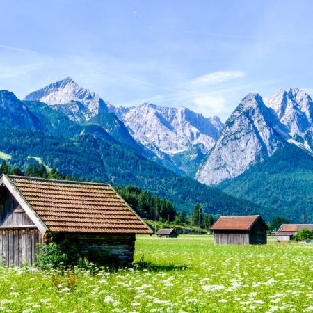 Ein Symbolbild der Höllentalangerhütte mit Waxenstein Alpspitze und Zugspitze im Hintergrund